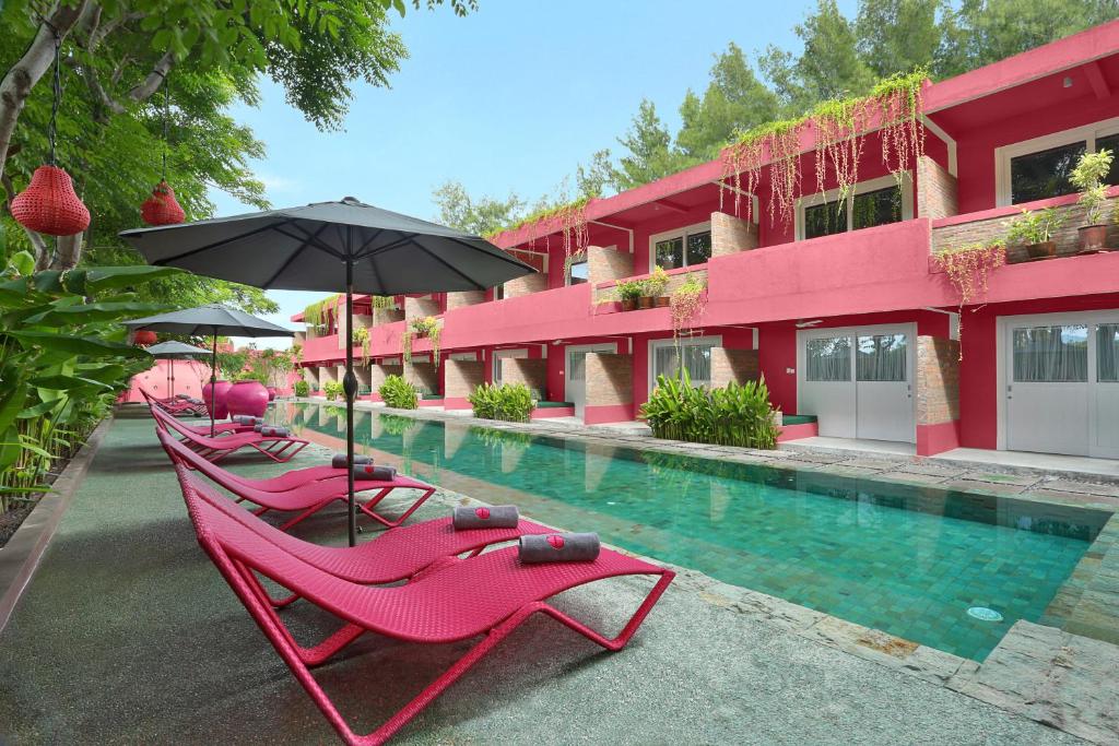 een rij roze stoelen en een parasol naast een zwembad bij PinkCoco Gili Trawangan - Constant Surprises - for Cool Adults Only in Gili Trawangan