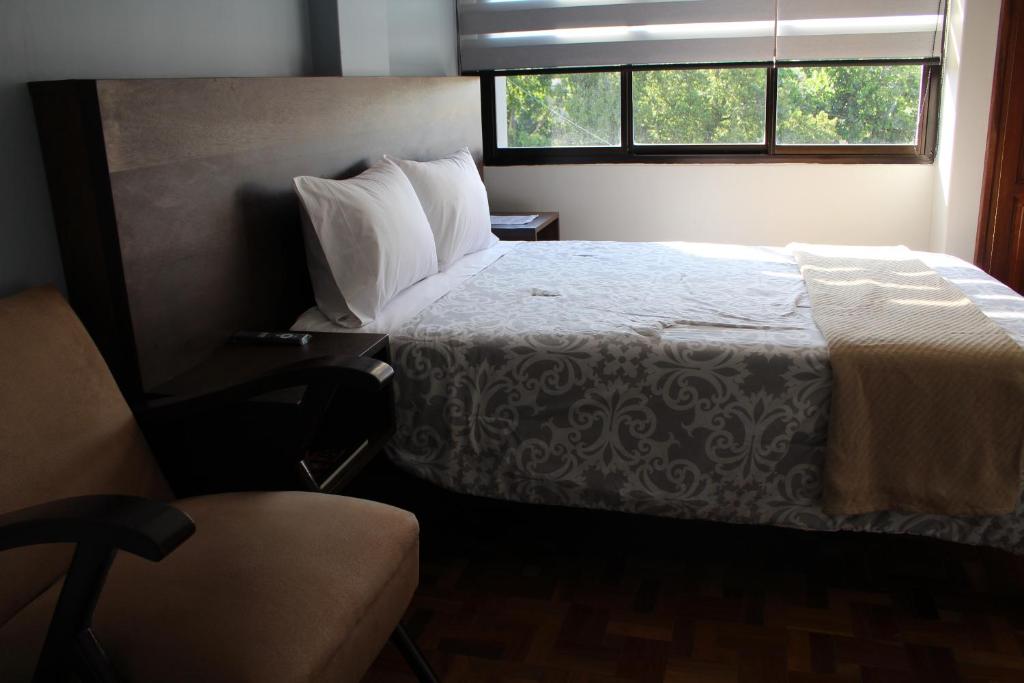 a bedroom with a bed and a chair and a window at Kunan Hotel in Cochabamba