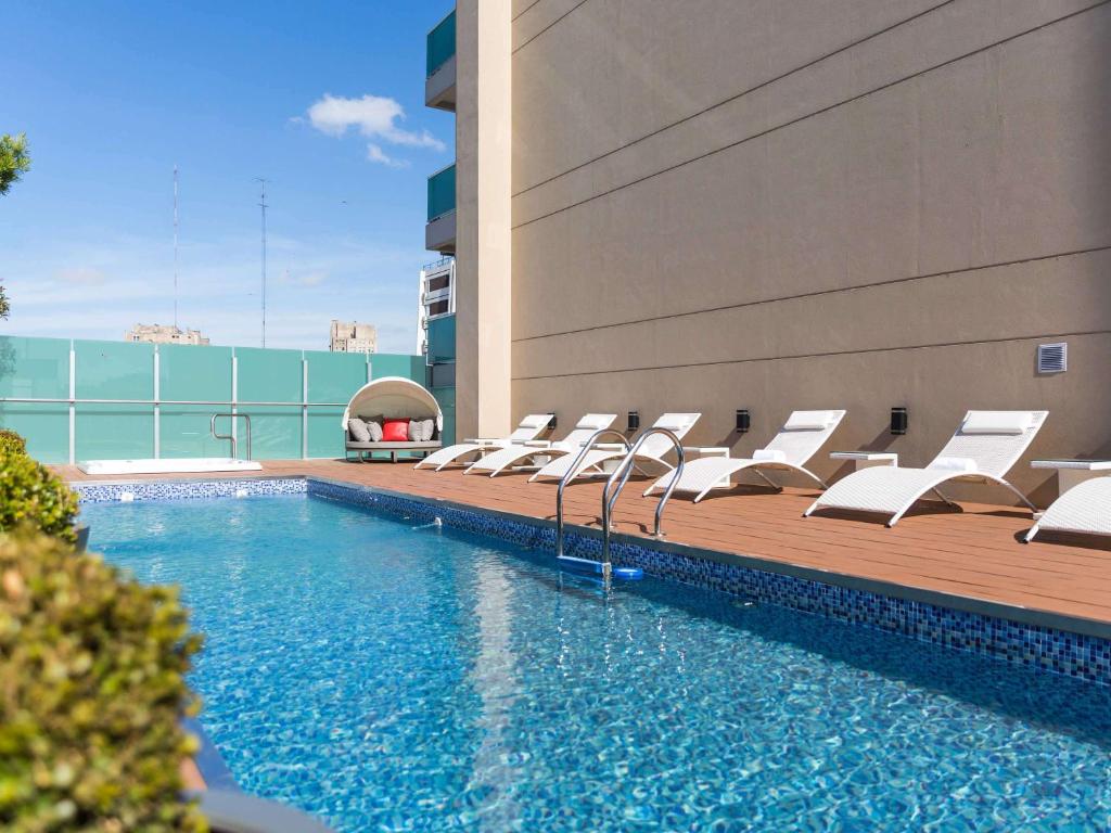 a pool with white lounge chairs next to a building at Palladio Hotel Buenos Aires - MGallery in Buenos Aires