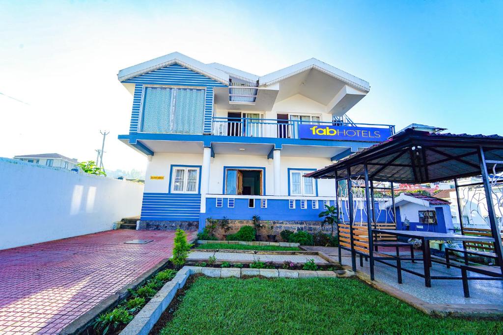 ein blau-weißes Haus mit einem Hof in der Unterkunft FabHotel Bala Garden in Udagamandalam