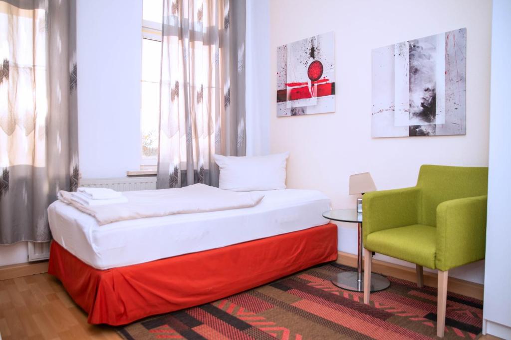 a bedroom with a bed and a green chair at Rothenberger Plauen in Plauen