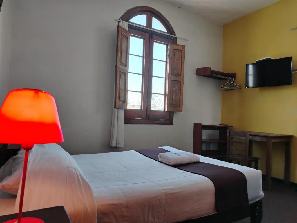 1 dormitorio con 1 cama con lámpara roja y ventana en La mansión del Monarca, en Arequipa