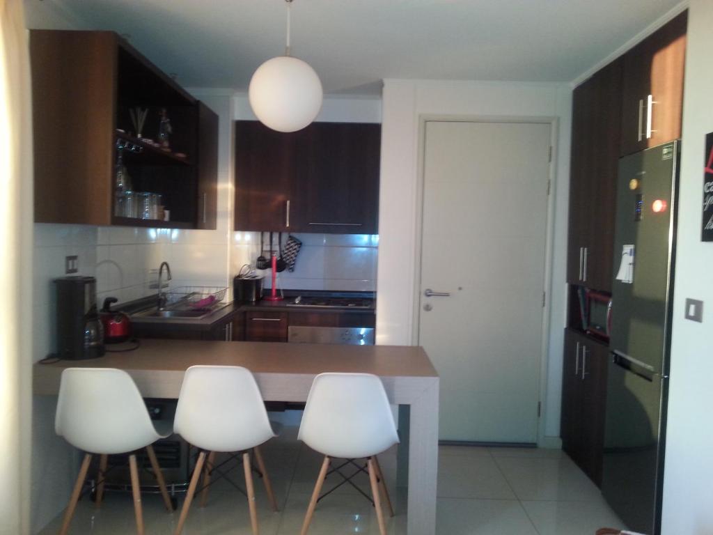 een keuken met een tafel en vier witte stoelen bij Apartamento Alemania in Temuco