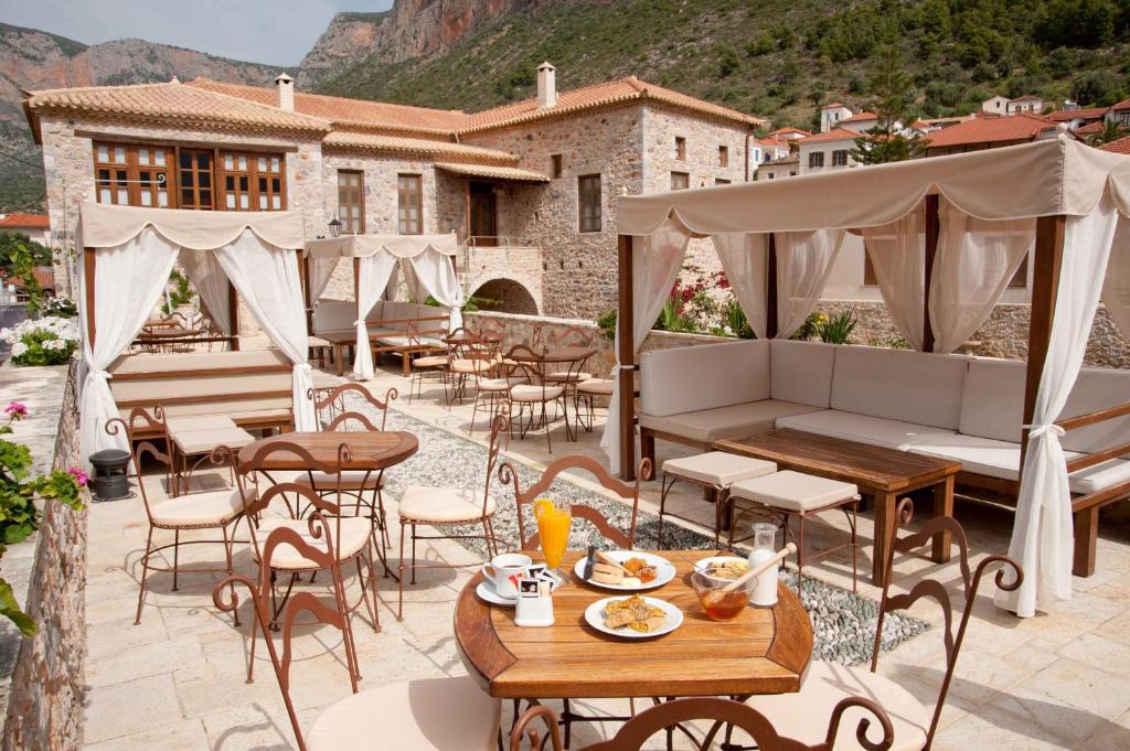 a patio with tables and chairs and a building at Archontiko Hatzipanayioti in Leonidion