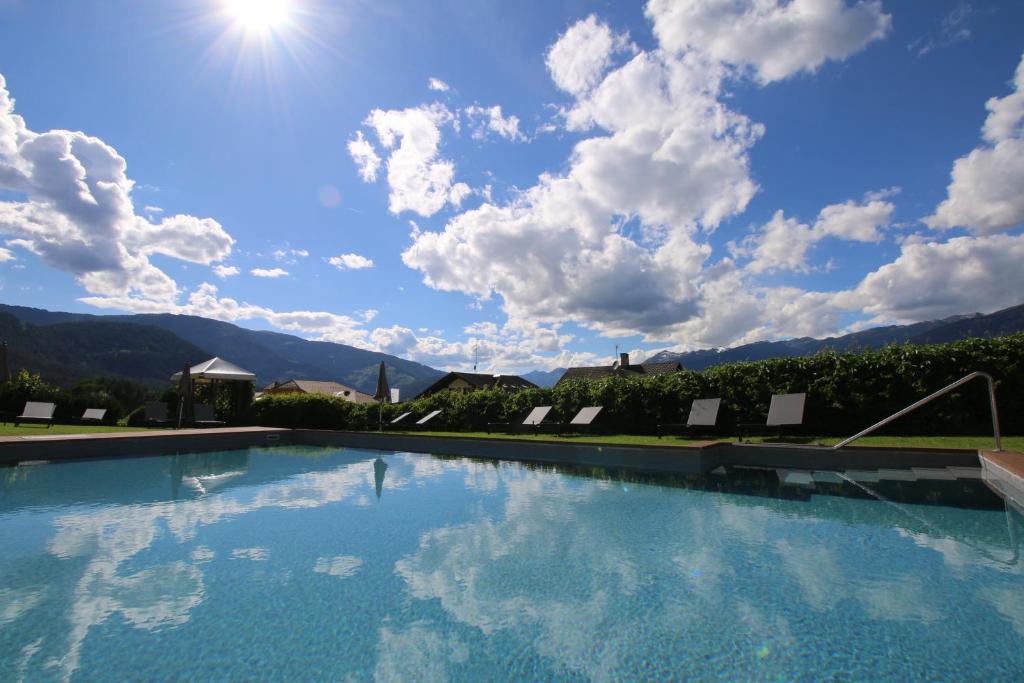 una gran piscina con un cielo azul con nubes en Hotel Lindnerhof, en San Lorenzo di Sebato