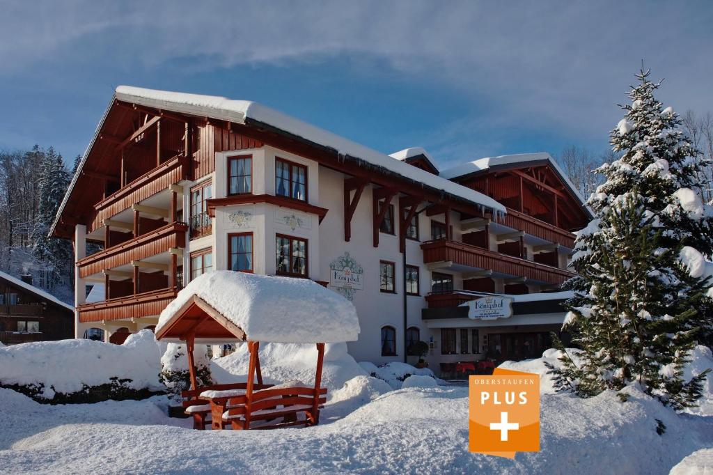 um edifício coberto de neve com um sinal em frente em Königshof Hotel Resort em Oberstaufen