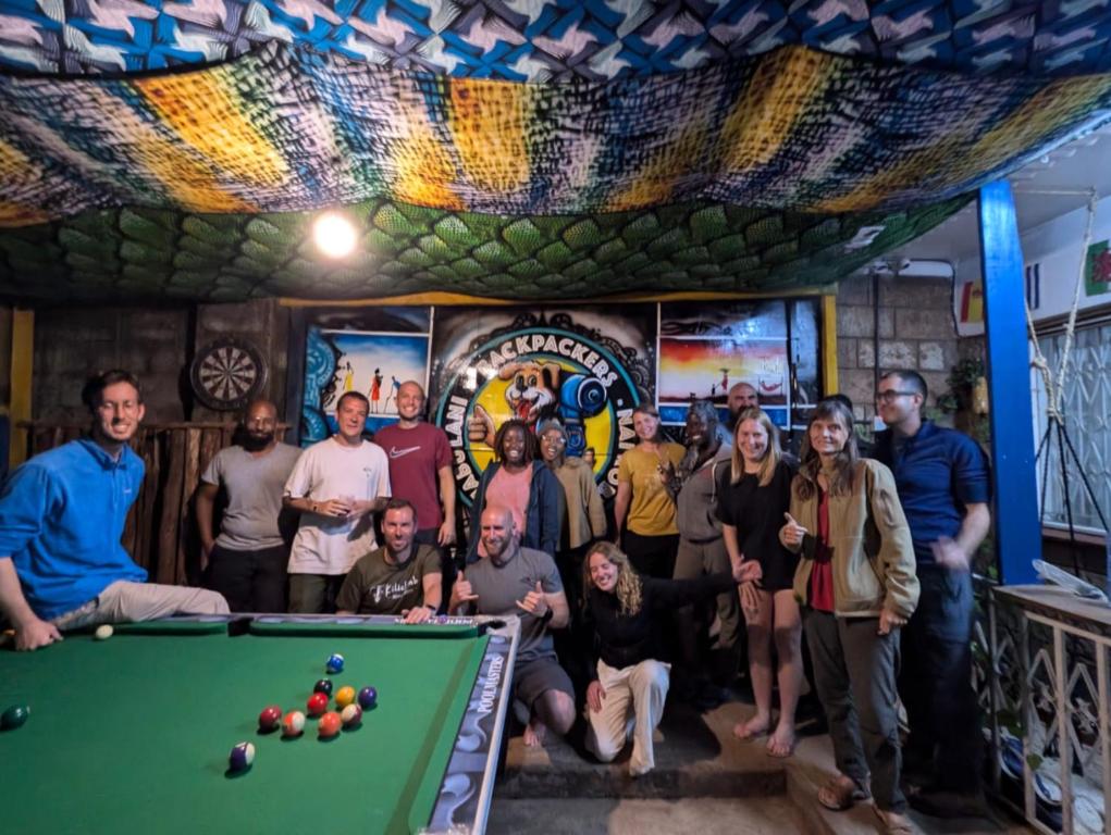 un grupo de personas de pie alrededor de una mesa de billar en Jabulani Nairobi Backpackers Hostel, en Nairobi