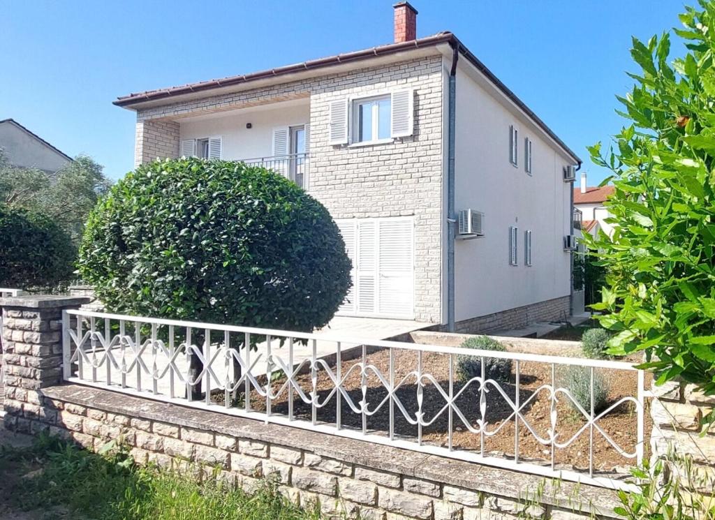 uma casa com uma cerca em frente em Apartment Korni em Biograd na Moru