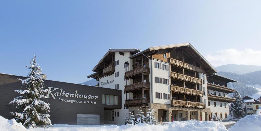 un bâtiment dans la neige avec un sapin de Noël dans l'établissement Das gemütliche Dorfhotel Kaltenhauser, à Hollersbach im Pinzgau