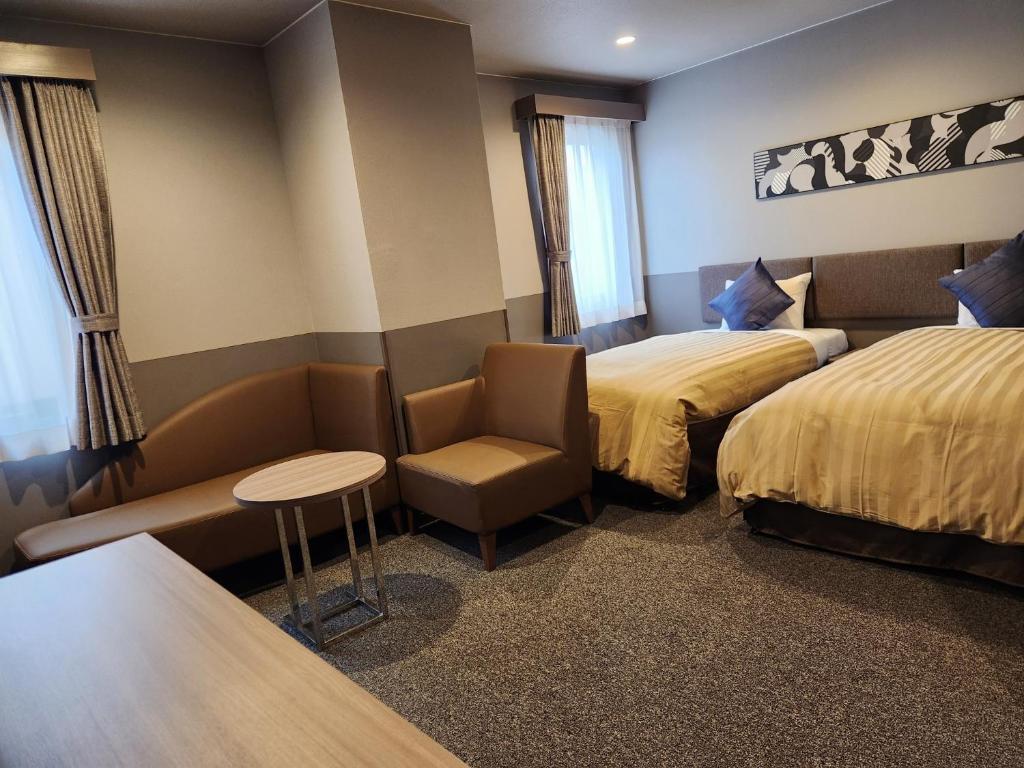 una camera d'albergo con due letti, una sedia e un tavolo di Sun Royal Kawasaki - Vacation STAY 54513v a Kawasaki