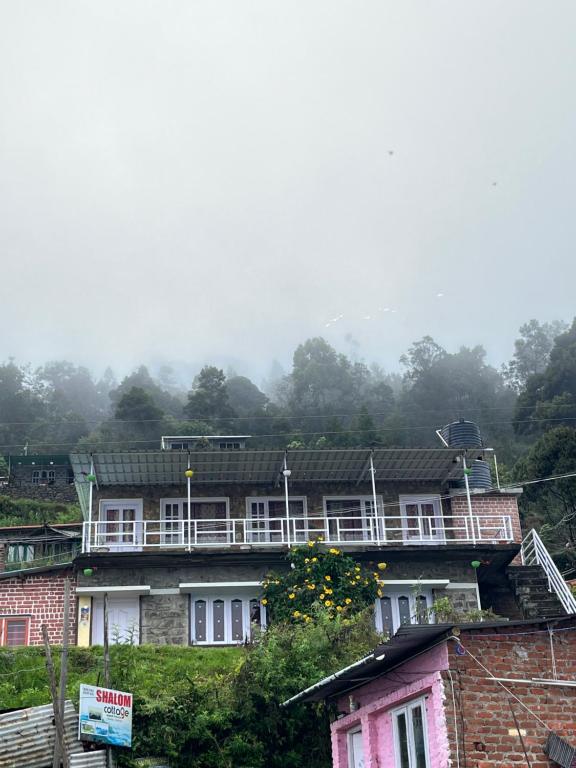 a building on a hill with trees in the background at AG Cottage Vattakanal in Kodaikānāl