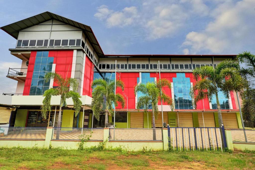 a building with palm trees in front of it at Collection O Coorg formerly Hotel Aravind Premier in Madikeri