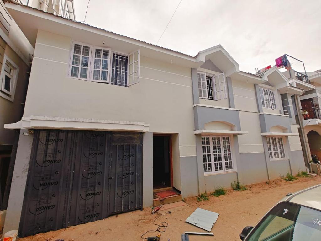 a white house with a garage in front of it at hilldown cottage in Ooty