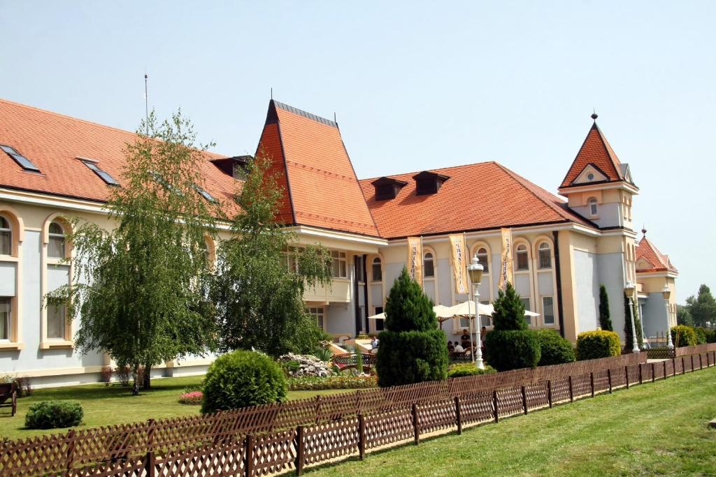 ein Gebäude mit einem Zaun vor einem Hof in der Unterkunft Hotel Prezident in Palić