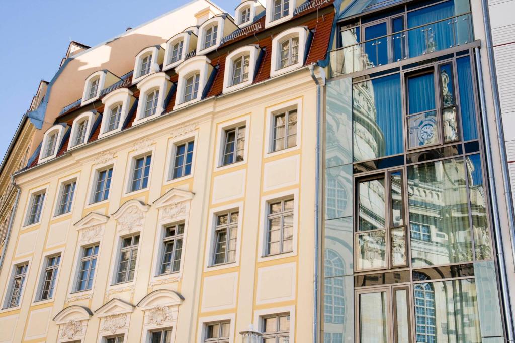 ein großes gelbes Gebäude mit Glasfassade in der Unterkunft Aparthotel Altes Dresden in Dresden