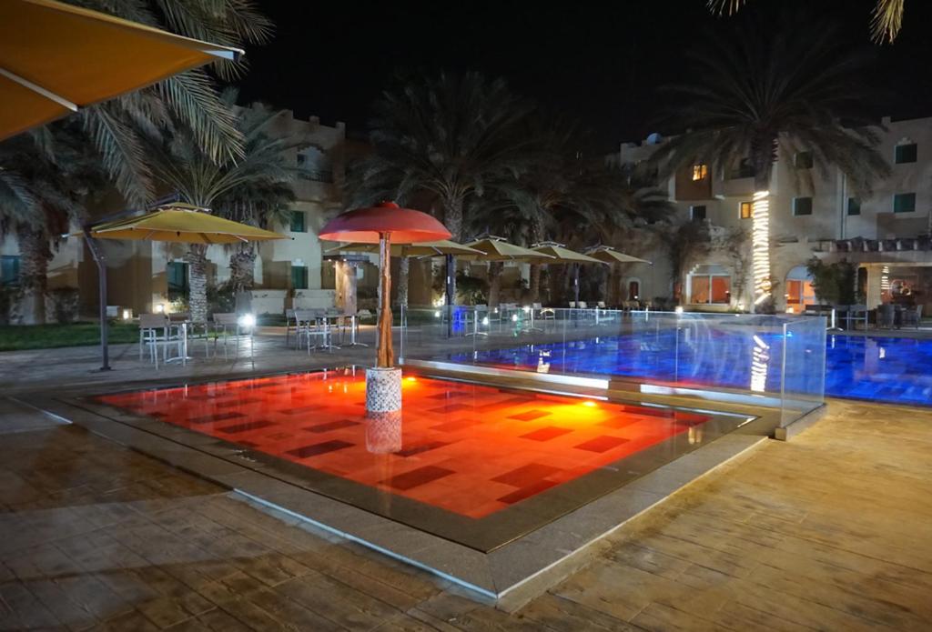 ein Pool mit einem roten Regenschirm in der Mitte in der Unterkunft Sahara Douz in Douz