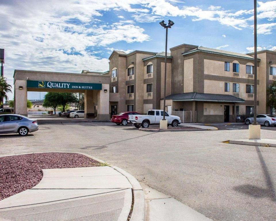 Quality Inn & Suites Yuma في يوما: مبنى فيه سيارات متوقفة في موقف للسيارات