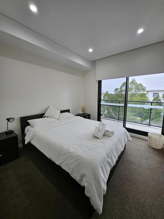 een witte slaapkamer met een groot bed en een groot raam bij Rouse Hills TownCentre luxury accommodation in Kellyville