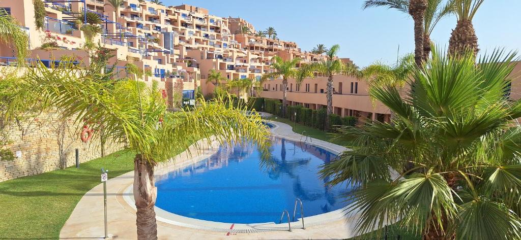 uma grande piscina com palmeiras em frente a um edifício em Sea view cozy apartment La Tanita em Mojácar