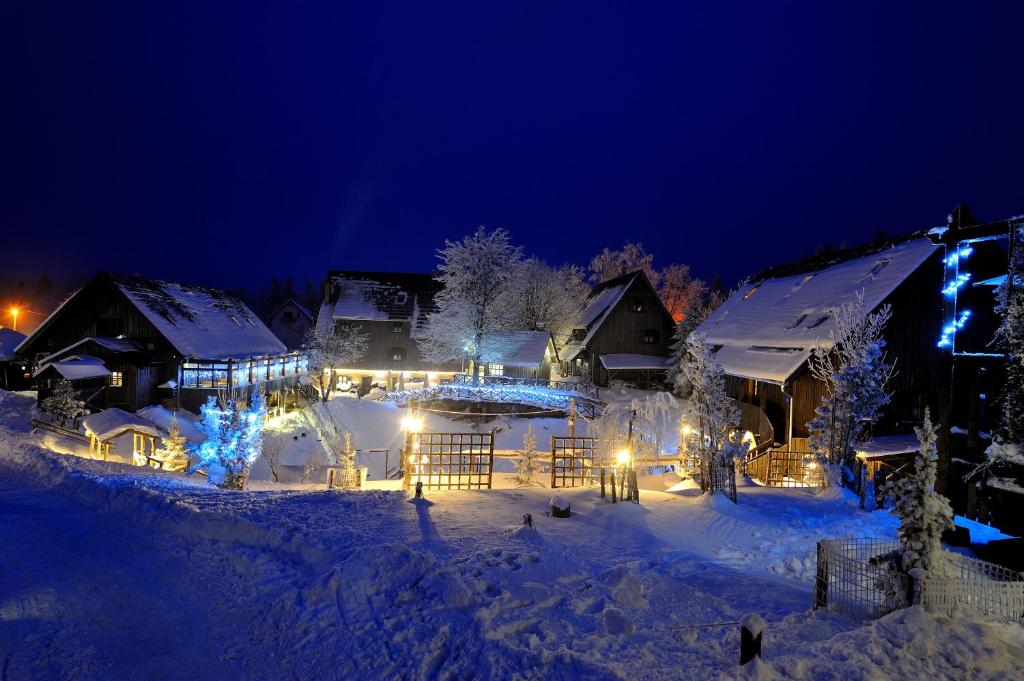 een resort in de sneeuw 's nachts met verlichting bij Ethno Houses Plitvice Lakes Hotel in Plitvica selo