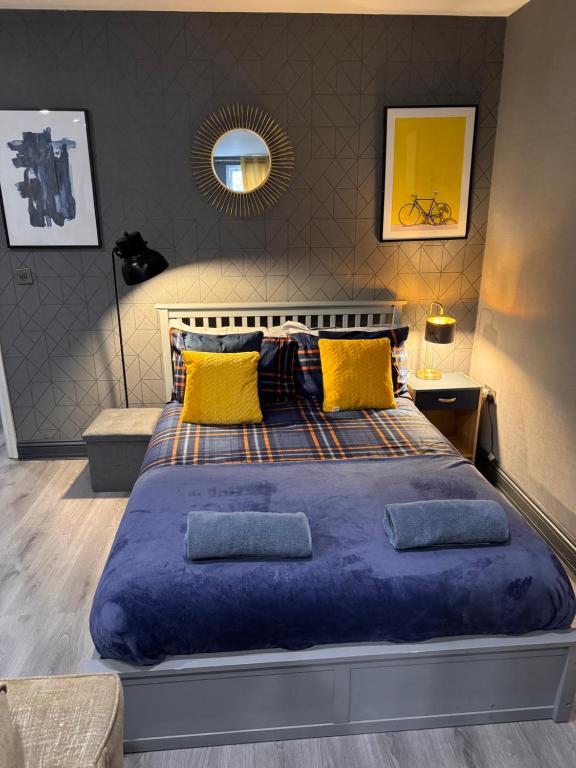 uma cama grande com um edredão azul e almofadas amarelas em Stylish Studio Flat With Private Patio em Bournemouth