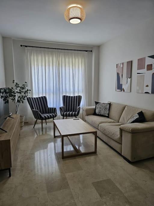 ein Wohnzimmer mit einem Sofa, Stühlen und einem Tisch in der Unterkunft Apartamento en Dos Hermanas La Motilla in Dos Hermanas