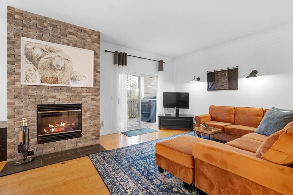 ein Wohnzimmer mit einem Sofa und einem Kamin in der Unterkunft Le Champetre Tremblant 2bdrs Condo W Fireplace in Mont-Tremblant