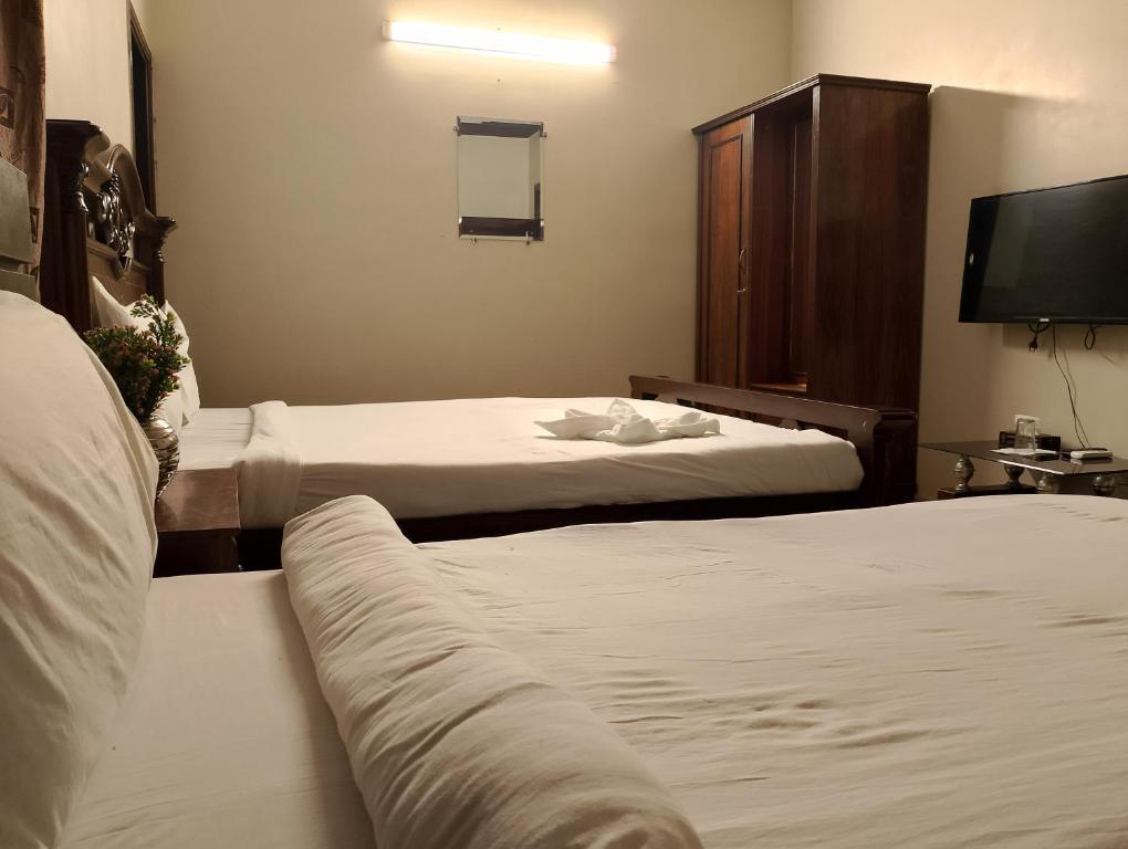 um quarto de hotel com duas camas e uma televisão de ecrã plano em Luxury inn Rooms near Expo center , air port , agha khan em Carachi