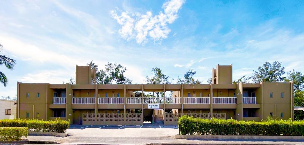 a tan building with a balcony in front of it at Scallop Beach Condominium in Onna