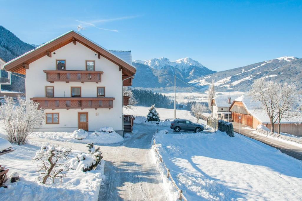 een huis in de sneeuw met bergen op de achtergrond bij Appartements Wiesenheim in Rasun di Sopra