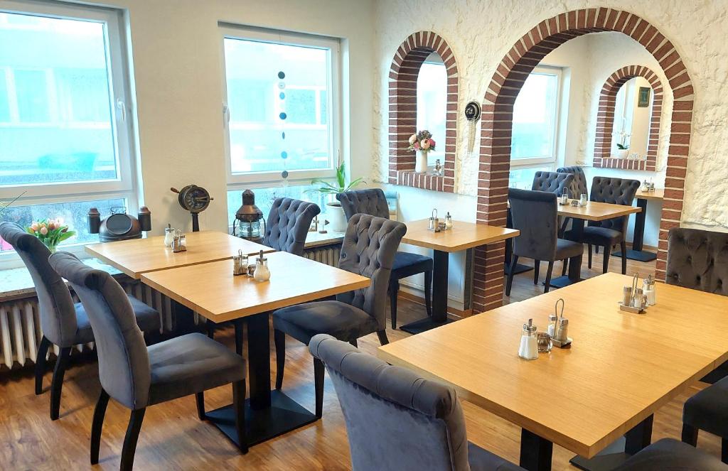 un restaurante con mesas y sillas de madera y ventanas en Hotel Villa Weststrand, en Borkum