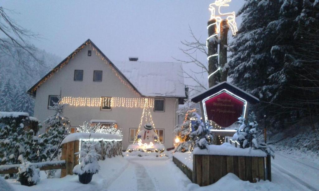 Una casa coperta di luci natalizie nella neve di Waldpension Pfeiferhaus a Warmensteinach