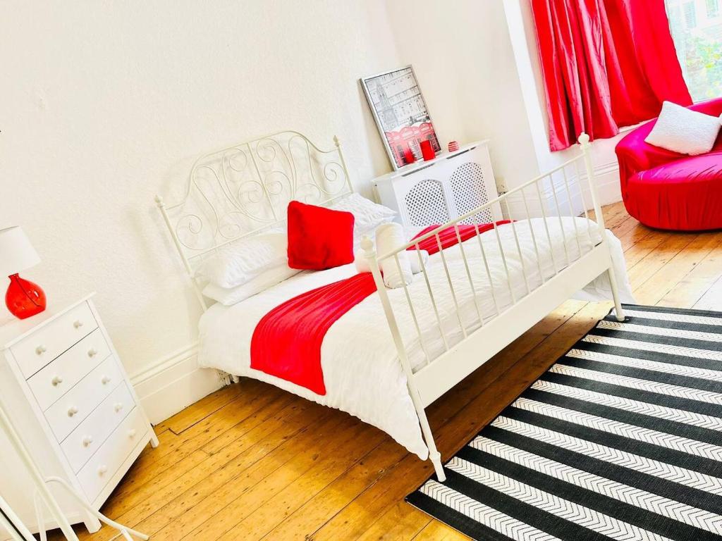 un letto bianco in una stanza con sedia rossa di Taswell House a Portsmouth