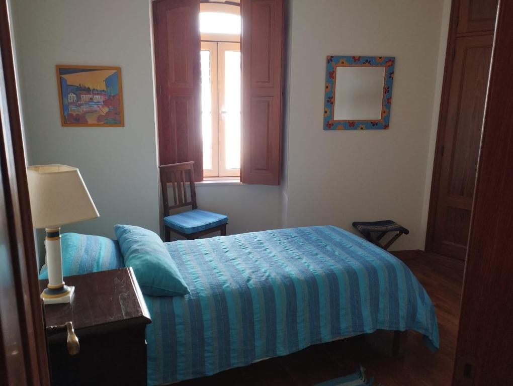 Un dormitorio con una cama azul y una ventana en Dom Camilo Alojamento local, en Minde