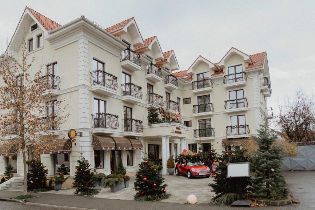 um grande edifício branco com árvores de Natal em frente em Radsor Hotel em Rîşnov