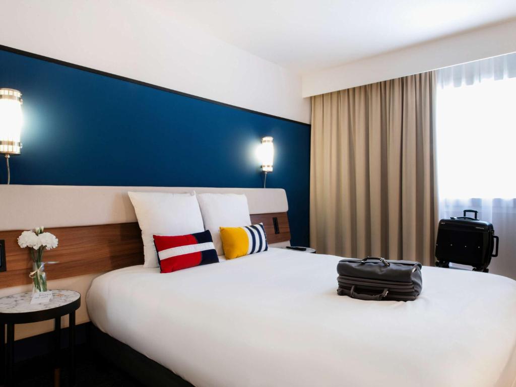 um quarto de hotel com uma cama grande com um saco em Mercure Caen Centre Port De Plaisance em Caen