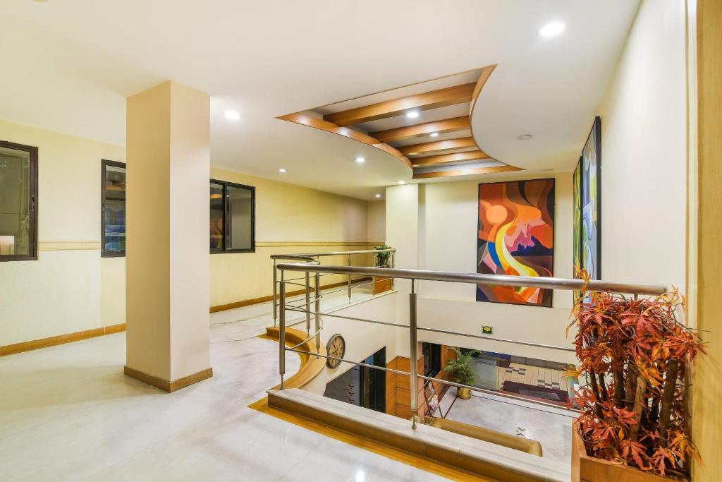 a lobby with a staircase and a painting on the wall at Capital O Grand Plaza in Coimbatore