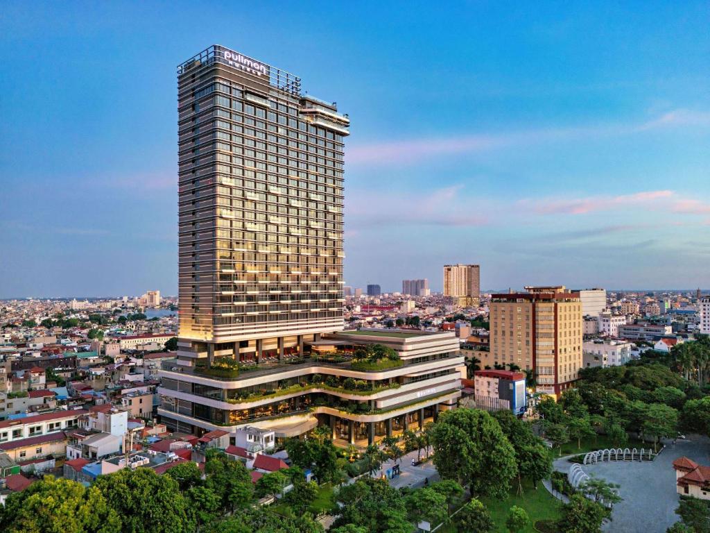 um edifício alto com muitas janelas numa cidade em Pullman Hai Phong Grand Hotel em Hai Phong