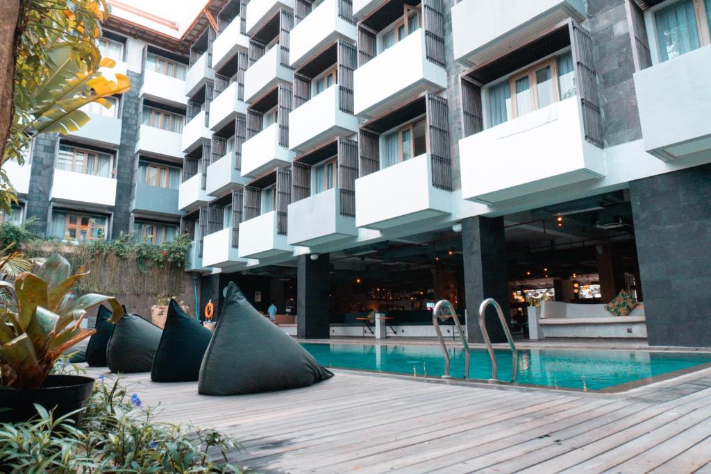 a hotel with a swimming pool in front of a building at IKOSHAROLD Suites Seminyak in Seminyak