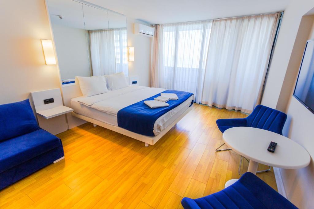 a bedroom with a bed and two blue chairs at VIP APARTmENTS N10 in Batumi