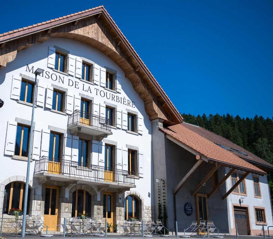 um edifício branco com um cartaz em Hôtel-Restaurant du Cerf em Les Ponts-de-Martel