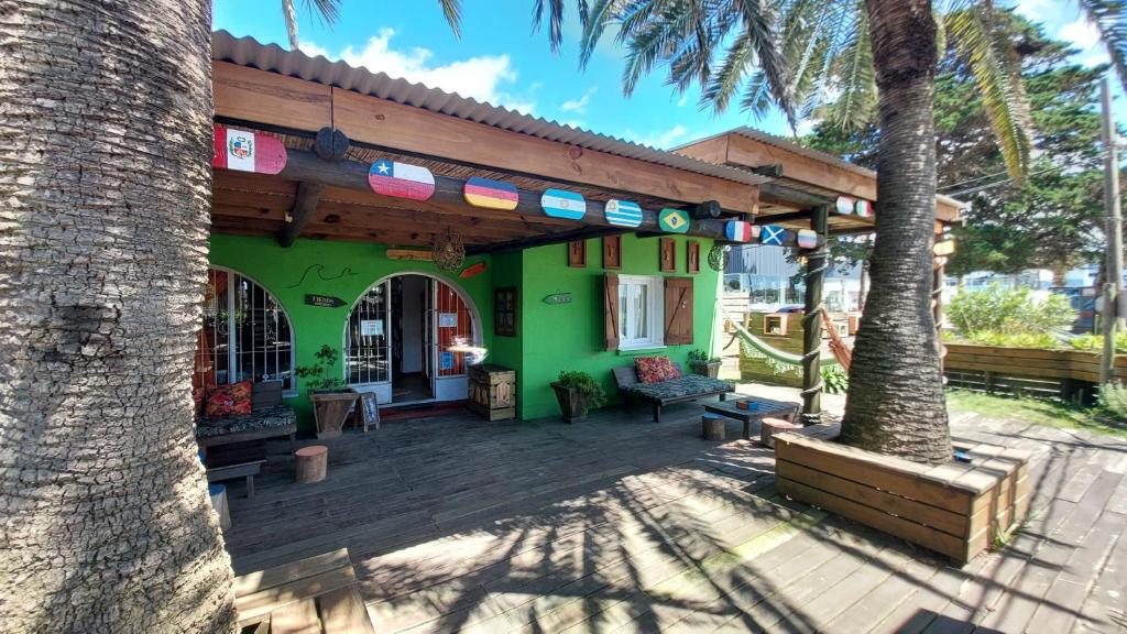 un edificio verde con una terrazza con due palme di Las Palmas Beach Hostel a La Paloma