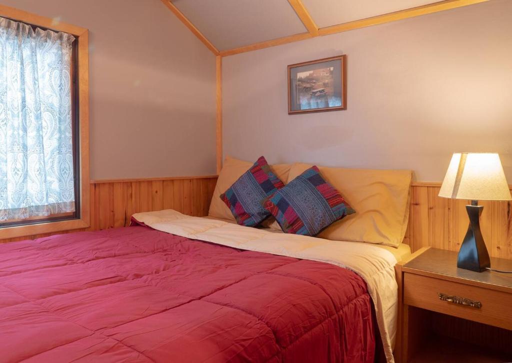 - une chambre avec un lit et une couverture rouge dans l'établissement Hillside Bungalows, à Banff