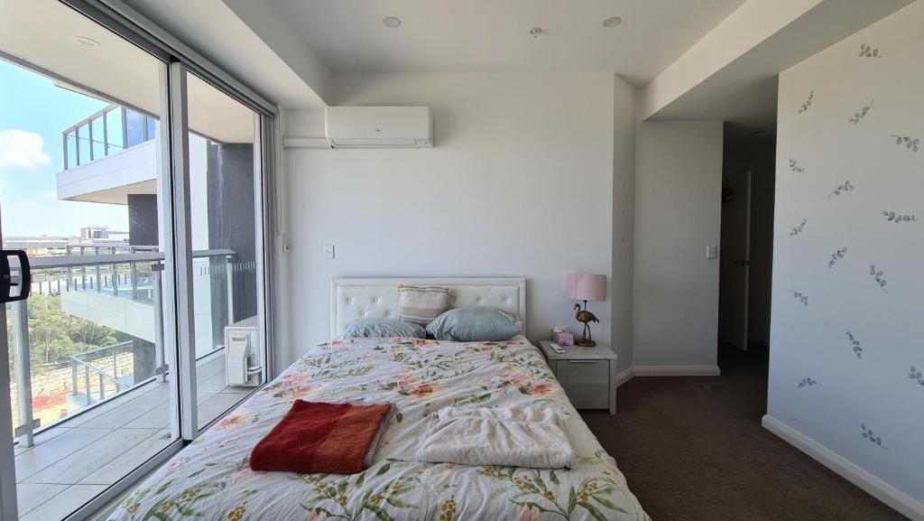 een slaapkamer met een bed en een groot raam bij Spacious 3 bedroom, 2 washroom and 2 parking 5 min from train station in Blacktown