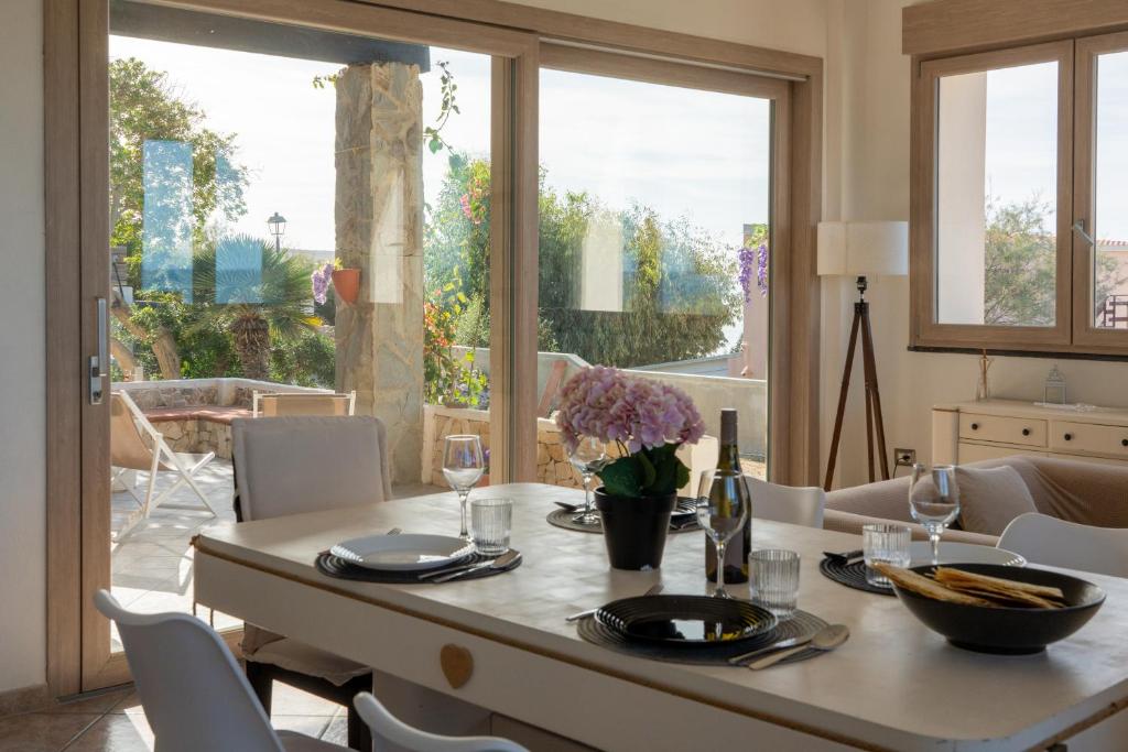 een eetkamer met een tafel, stoelen en ramen bij Villa Amea in Torre Dei Corsari