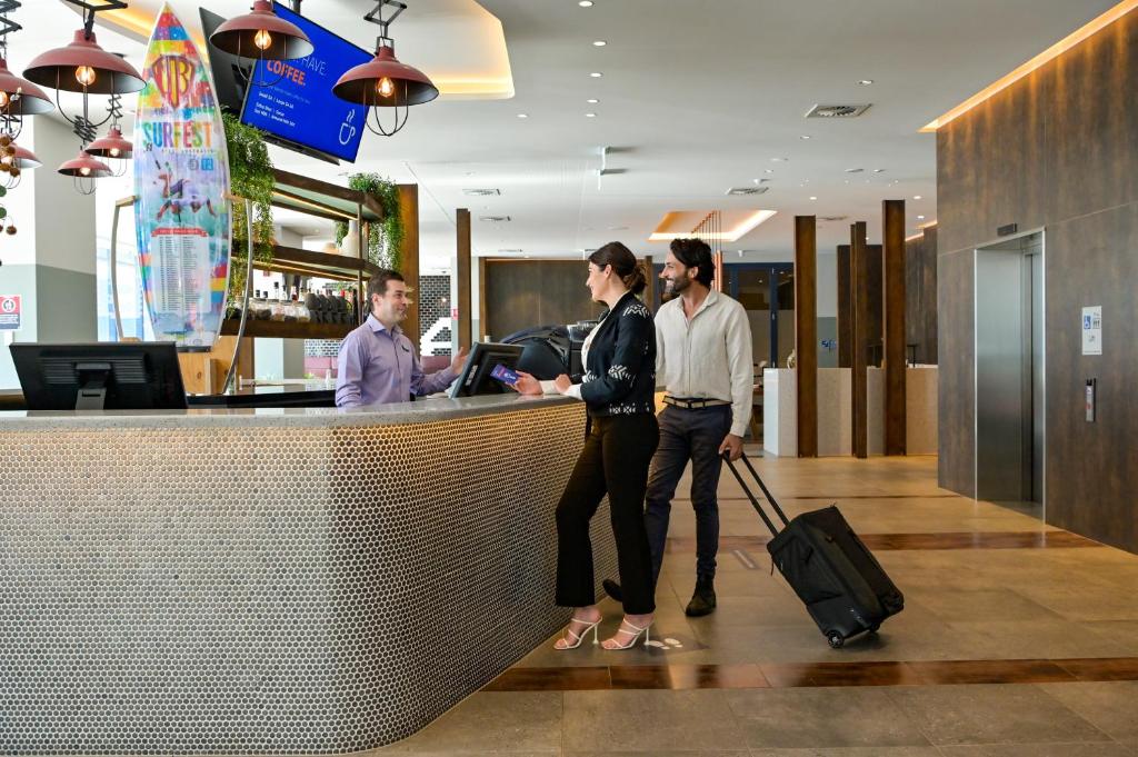 due donne in piedi al bancone della reception in un aeroporto di Holiday Inn Express Newcastle, an IHG Hotel a Newcastle