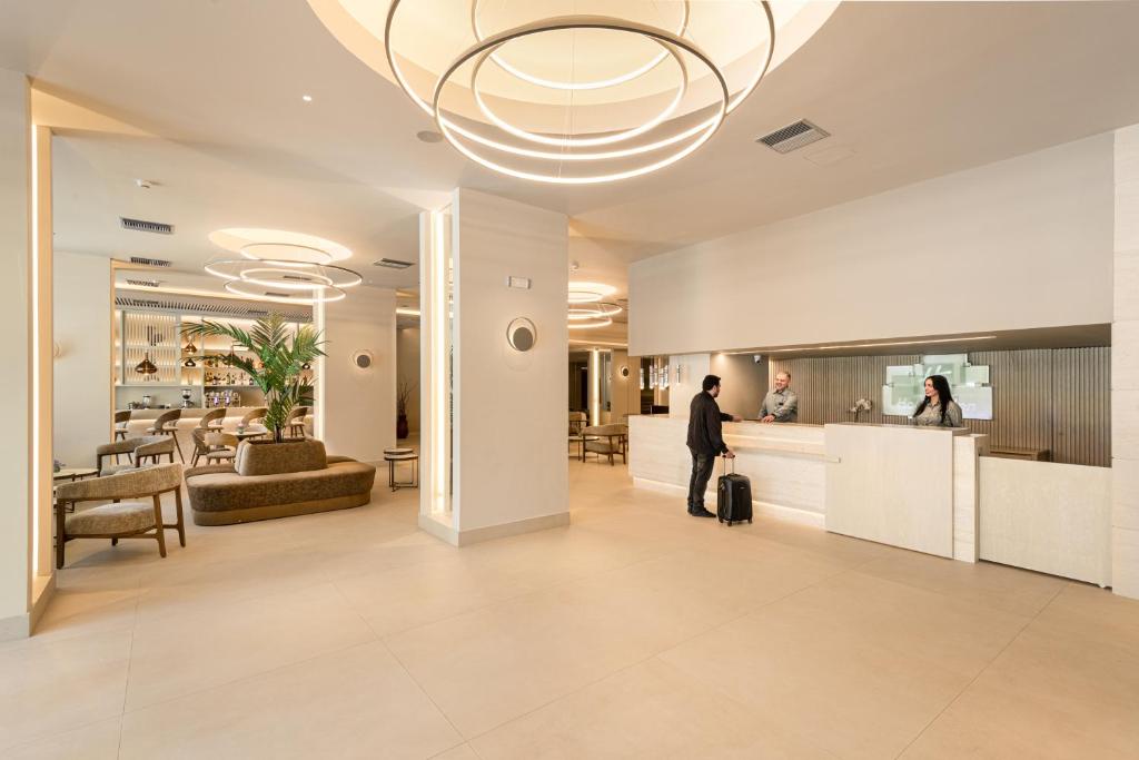 un homme debout dans un hall avec une valise dans l'établissement Holiday Inn Thessaloniki, an IHG Hotel, à Thessalonique