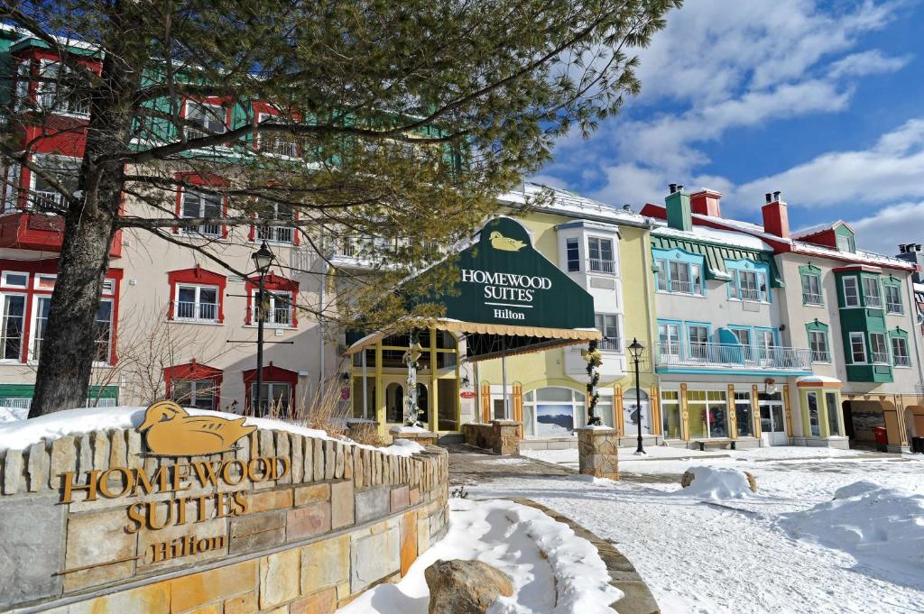 ein Schild für die heimeligen Suiten in einer schneebedeckten Straße in der Unterkunft Homewood Suites by Hilton Mont-Tremblant Resort in Mont-Tremblant