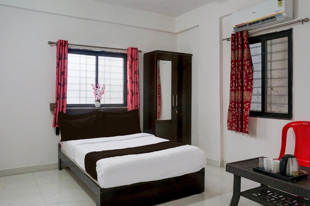 um quarto com uma cama e uma janela com cortinas vermelhas em Super Hotel O Manjari Road em Pune