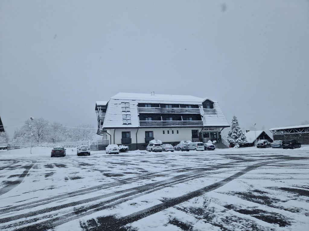 um edifício coberto de neve com carros estacionados num parque de estacionamento em New Wolf em Bran